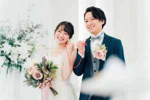 結婚式場で赤い糸で結ばれる新郎新婦の写真