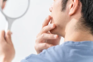 鏡を見て身なりを整えている男性の写真