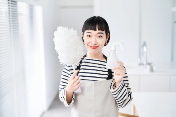 掃除道具を持って笑顔を見せる女性の様子