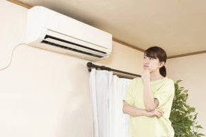 エアコンの前の考える女性の写真