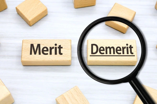 Demeritと書かれた木製ブロックを虫眼鏡で見ている画像