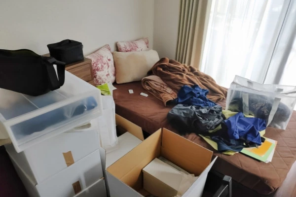 衣類や段ボールなどで散らかった部屋の様子
