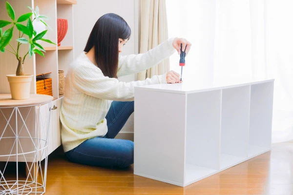 カラーボックスを分解する女性の写真
