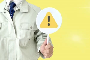 注意マークを持った作業員の写真