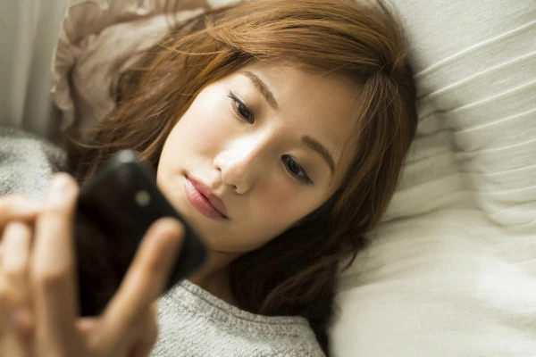 スマホを見ながら悩む女性の写真