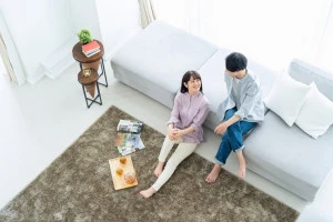 ラグを敷いた床の上でくつろぐ男女の写真