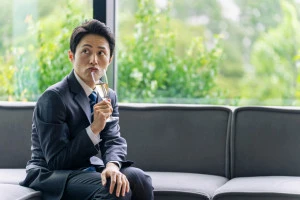 浮かない表情でシャンパンを飲むスーツを着た男性の写真
