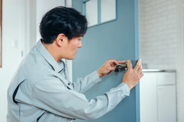 作業服のスタッフがドアの錠前を交換している様子