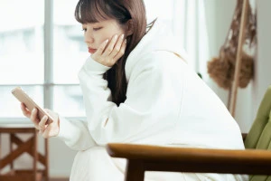 スマホ見て浮かない顔をしている女性の写真