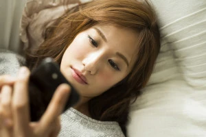 スマホを見ながら悩む女性の写真