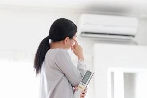 エアコンの前で悩む女性の写真