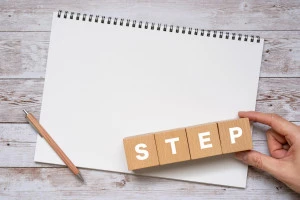 STEPと書かれたブロック、ノート、ペン、手の画像