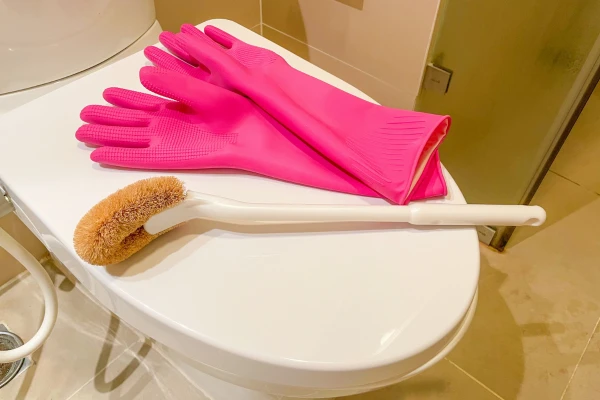 トイレのフタの上にゴム手袋とたわしが置かれている様子
