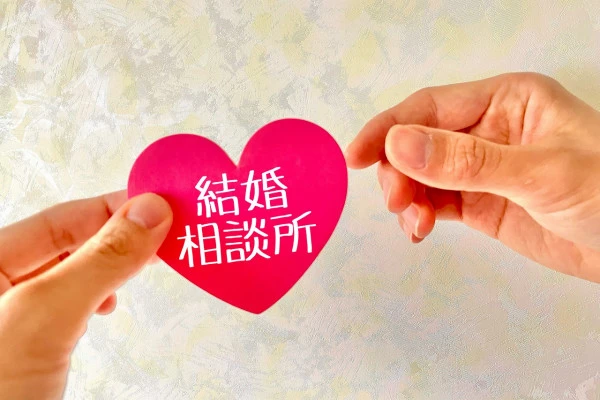 結婚相談所と書かれたハートをつまむ指の写真