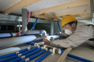 住宅の床下の排水管を点検する作業服の男性の写真