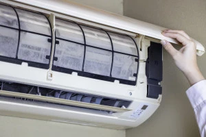 汚れたエアコンフィルターと点検をする女性の手元の写真