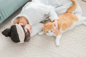 床に寝転ぶ女性と猫の写真