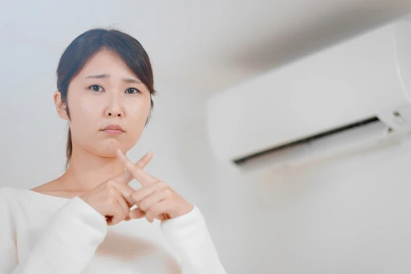 エアコンを背景にバッテンをする女性