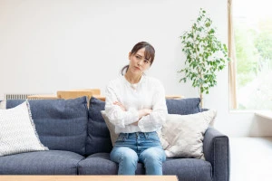 ソファに座って悩む人の写真