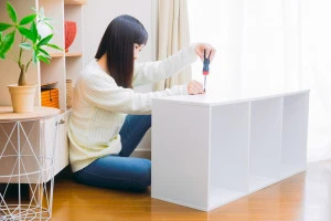 カラーボックスを分解する女性の写真