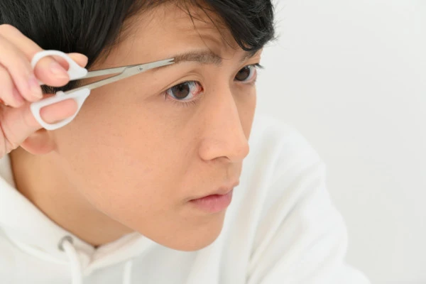 自分で眉毛を整える男性の写真