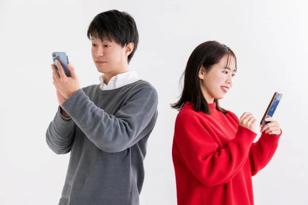 スマホを見る男女の写真