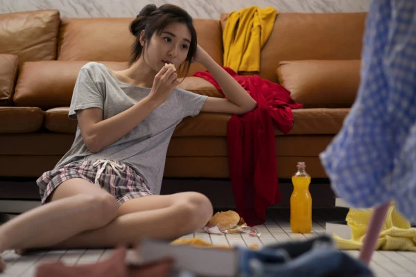散らかった部屋にいる疲れた表情の女性