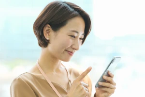 笑顔でスマホを使う女性の写真