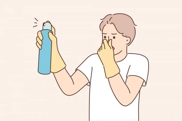 鼻をつまみながらスプレーを噴射する男性