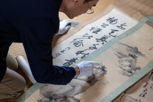 掛け軸の査定を行う男性の写真