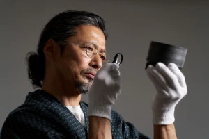 ルーペで骨董品を見つめる男性の写真