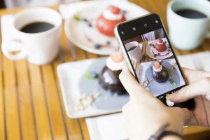 ケーキの写真をスマホで撮影をする女性の手元写真