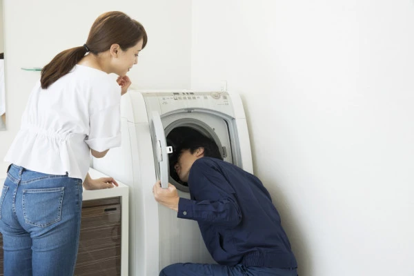 洗濯機の点検を行う業者の写真
