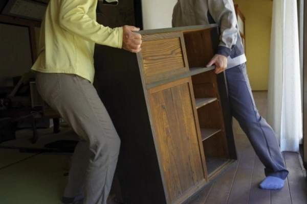 2人の男性が古いタンスを運ぶ