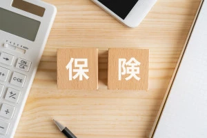 保険と書かれたブロック、電卓、スマホ、ノートの画像
