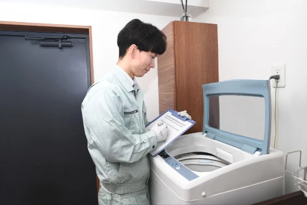 洗濯機を点検している作業員の画像