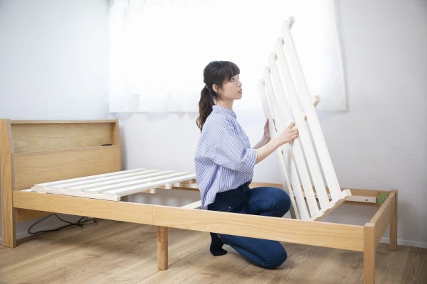 ベッドからすのこを外す女性の写真