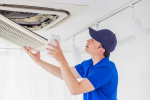 天井埋め込みエアコンの点検をする作業員の写真