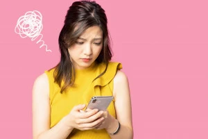 スマホが壊れて困っている女性の写真