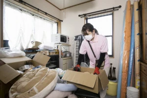 散らかった部屋を片付ける女性作業員の写真