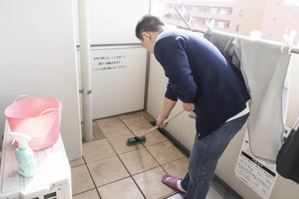 マンションのベランダの掃除をする男性