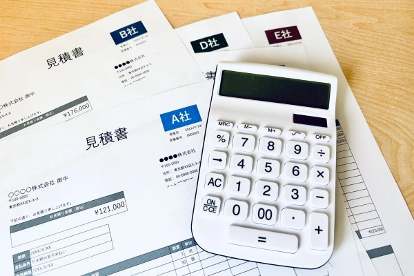 複数社の見積書と電卓の画像