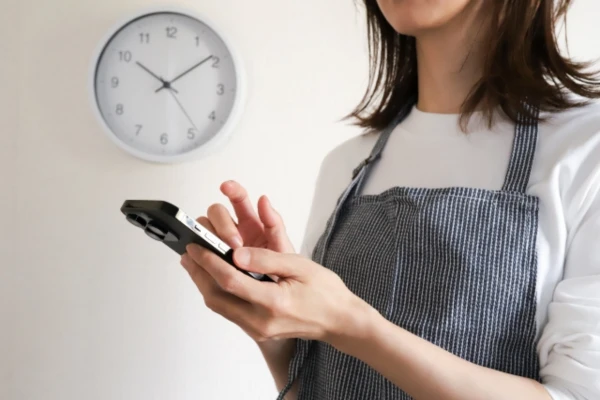 家の中でスマホを手に取っている女性