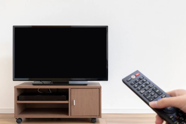 テレビのリモコンを操作する手とテレビ画面の画像