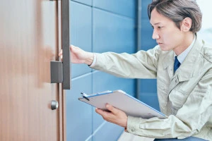 ドアをチェックする作業服姿の若い男性の写真