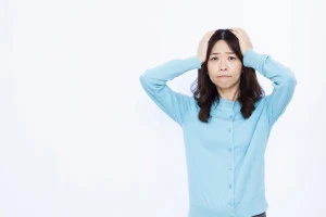 頭を抱えて悩む女性の写真