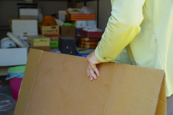 物が多い部屋で段ボールを持った人がいる
