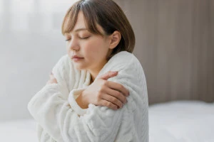 部屋の中で寒がる女性の写真