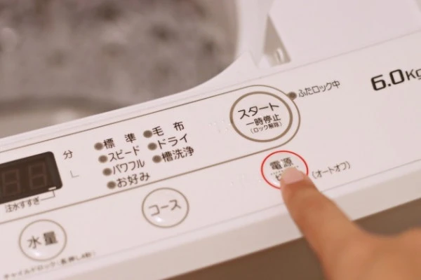 洗濯機の給水ホースから水漏れしたため電源を切る様子