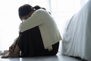 床に座って落ち込む女性の写真